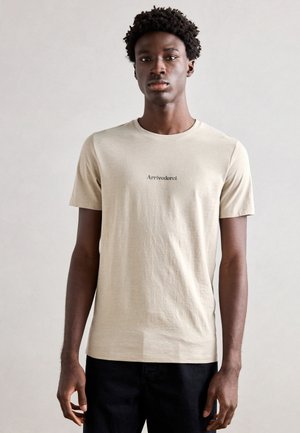 Lichtbeige t-shirt met korte mouwen en een ronde halslijn, voorzien van zwarte "Arrivederci" tekst op de voorkant, gemaakt van zachte, gestructureerde stof.