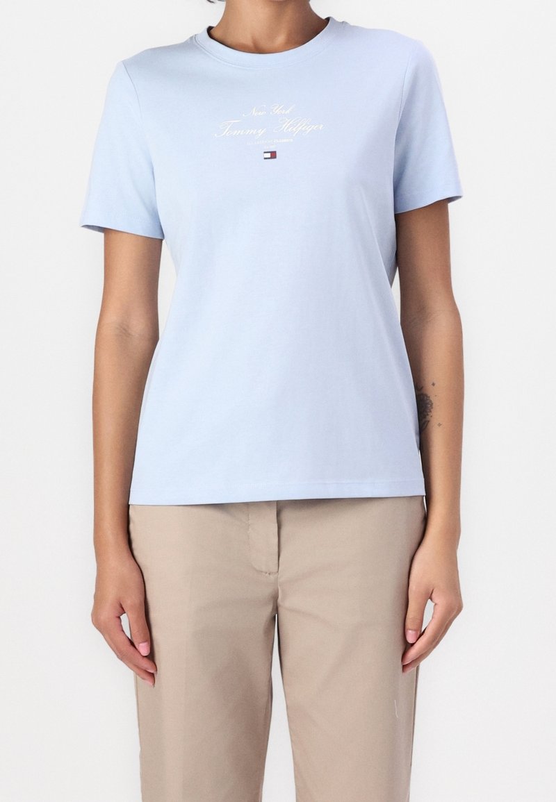 Ljusblå bomullströja med kort ärm, rund halsringning och logotext i vit och röd tryck. Enfärgad, avslappnad passform.