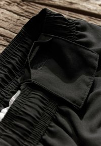 Fekete sportshort, elasztikus derékkal és kis belső zsebbel, tépőzáras záródással, sima, tartós anyagból készült.