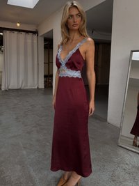 Burgundy satin dress with lace trim and a cutout at the waist, featuring a V-neck design. Smooth texture and floor-length silhouette.