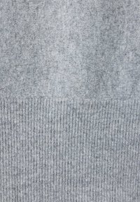 Tissu gris doux avec une partie supérieure lisse et une partie inférieure à texture côtelée, montrant les détails du matériau tricoté.