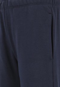 Navyblauwe katoenen sweatpants met een elastische tailleband, voorzien van een zijzak en een zachte, gladde textuur.