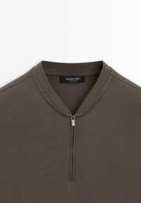 Brun langærmet top med en kort sølvlynlås ved kraven og en ribbet halsudskæring, mærket Massimo Dutti.