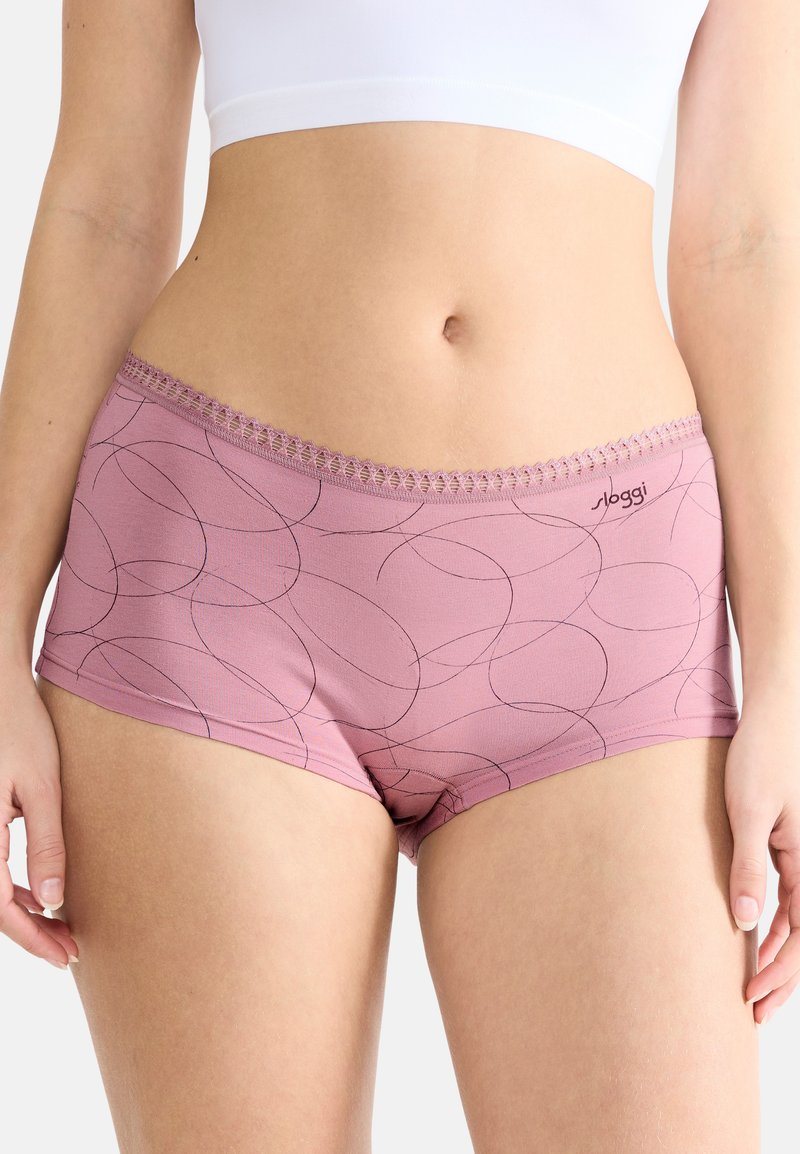 Jasnoróżowe majtki typu boyshorts o gładkiej teksturze, z czarnym okrągłym wzorem i dekoracyjną koronką na pasku w talii. Logo po boku.