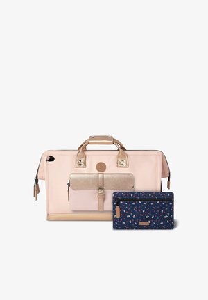 Sac fourre-tout rose clair avec des accents métalliques dorés roses, compartiment zippé et une pochette à motif floral bleu foncé. Tissu durable, design structuré.
