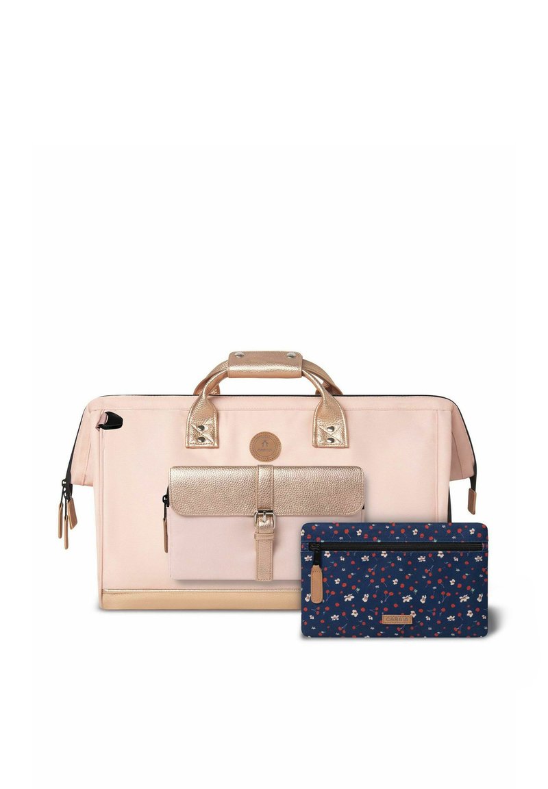 Sac fourre-tout rose clair avec des accents métalliques dorés roses, compartiment zippé et une pochette à motif floral bleu foncé. Tissu durable, design structuré.