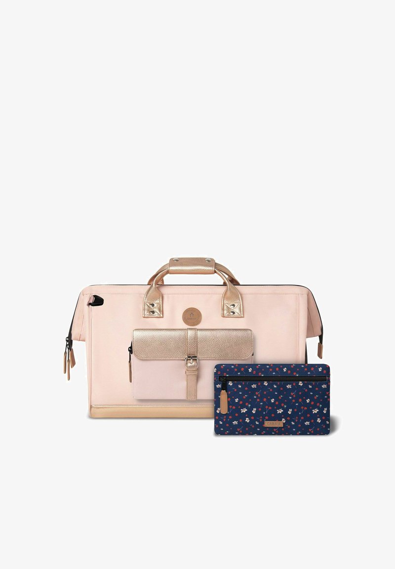 Sac fourre-tout rose clair avec des accents métalliques dorés roses, compartiment zippé et une pochette à motif floral bleu foncé. Tissu durable, design structuré.