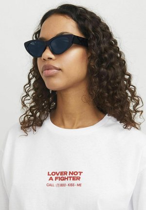 Black cat-eye sunglasses with dark lenses, worn with a white t-shirt featuring red text that reads "LOVER NOT A FIGHTER."