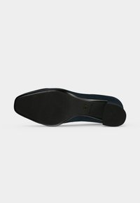 Semelle d'une chaussure habillée noire avec grip texturé sur l'avant et le talon, indiquant la taille 37 et le logo de la marque sur la zone de la voûte plantaire.