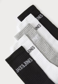 Set mit drei gerippten Socken in Schwarz, Weiß und Grau, die den Markennamen "JACK & JONES" in kontrastierender Farbe auf jeder Socke eingestickt haben.