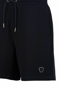 Donkerblauwe shorts van textuurstof, met een elastische tailleband en trekkoord, en een klein schildlogo geborduurd op het linkerpoot.