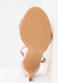 Sandale à talon haut en daim beige avec un talon fin, une bride cheville, une semelle texturée et la mention de taille "Anna Field 40" au-dessous.