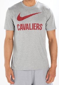 Camiseta de manga corta gris con el logo de Nike en rojo y el texto "CAVALIERS" en una fuente negrita en el pecho. Fabricada con un tejido suave y transpirable.