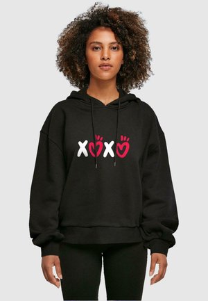 Čierna mikina s oversized strihom, na prednej strane s bielym a červeným grafickým nápisom "XOXO". Vyrobená z mäkkej, textúrované látky. S kapucňou na sťahovanie.