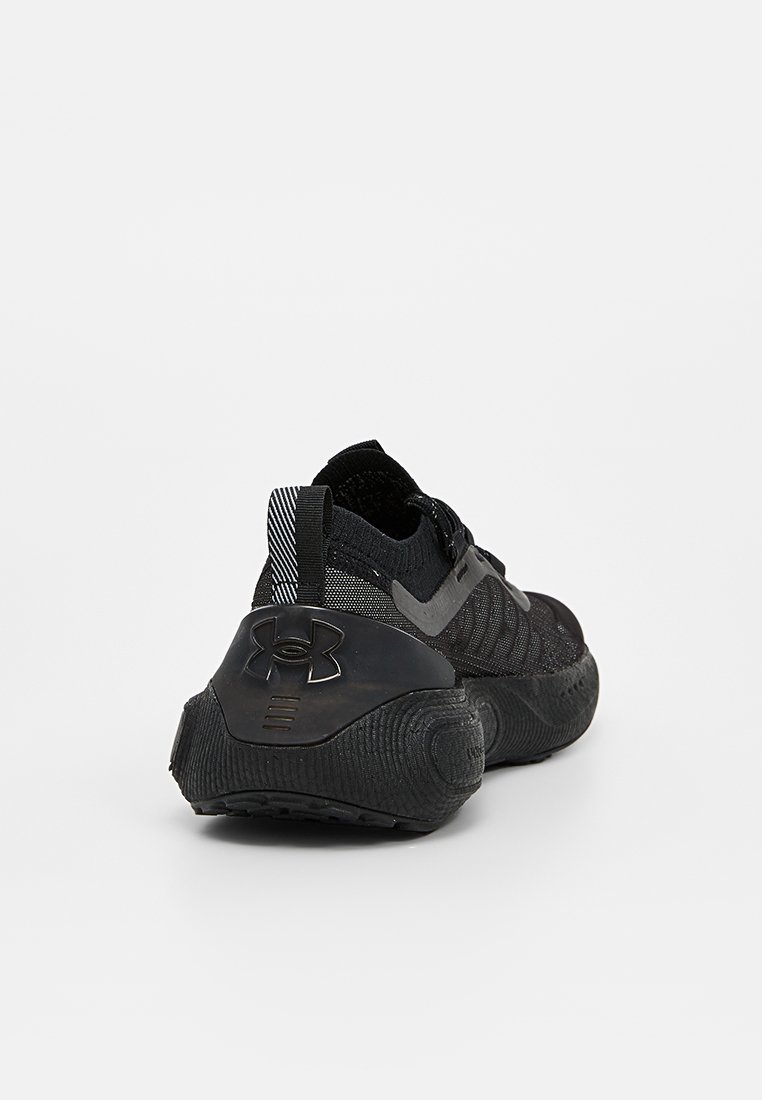 Scarpa sportiva nera con tomaia in maglia testurizzata, suola in gomma e un logo Under Armour ben visibile sul tallone, con accenti a righe sulla rete.