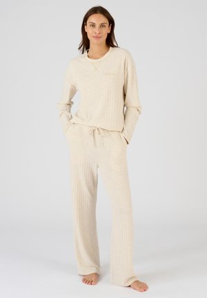 Beige geribbelde loungewear set met een lange mouw top met een ronde hals en broek met trekkoord in de taille. Zachte textuur en ontspannen pasvorm.