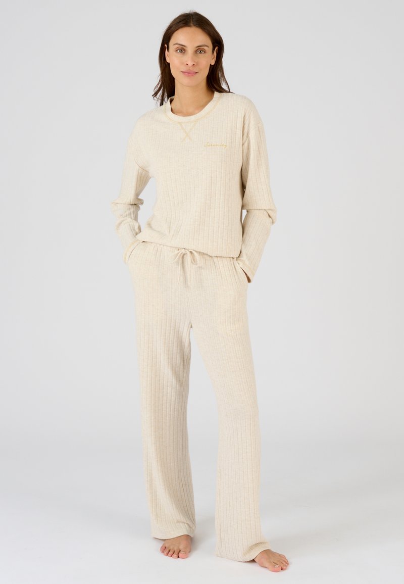 Set di abbigliamento loungewear a coste beige composto da una maglia a maniche lunghe con scollatura rotonda e pantaloni con vita regolabile. Tessuto morbido e vestibilità rilassata.