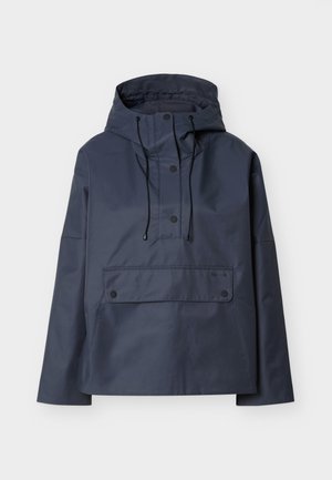 Σκούρο μπλε ναυτικού χρώματος αδιάβροχο αντιανεμικό με κουκούλα, με μπροστινές τσέπες με καπάκι και κρυφό κόπιτσα, απλωμένο επίπεδα σε ανοιχτό φόντο.