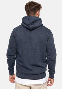 Sudadera de color azul marino hecha de una tela suave con un corte holgado, que cuenta con una gran capucha ajustable y puños y dobladillo de canalé.