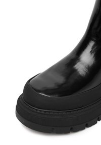 Czarne błyszczące botki za kostkę z okrągłym noskiem, grubą gumową podeszwą i fakturowanymi akcentami. Materiał jest gładki z błyszczącym wykończeniem.