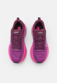 Scarpe da corsa viola con una parte superiore in rete, accenti rosa e una suola imbottita. Lacci di un viola scuro e logo bianco sul lato.