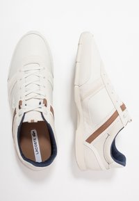 Sneaker bianche con un mix di pelle liscia e camoscio. Presentano dettagli marroni, lacci rotondi e un interno imbottito di colore blu navy.