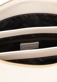 Interno di una borsa in pelle beige con rivestimento nero e marchio WITTCHEN. Presenta una sezione con zip e diversi scomparti per l'organizzazione.