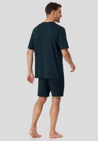 Camiseta de manga corta en color marino con un patrón sutil y pantalones cortos a juego, diseñados para la comodidad; la tela parece suave y tiene un corte relajado.
