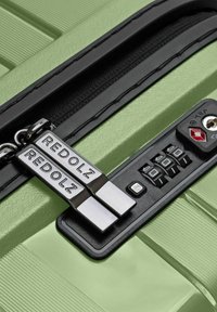 Valigia rigida verde chiaro con zip a doppio cursore etichettata "REDOLZ" e un lucchetto combinazione TSA nero impostato su 0-0-0.