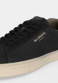 Μαύρο sneaker από δερμάτινη υφή με μαύρα κορδόνια, κρεμ φαρδύ λάστιχο και λογότυπο "ALLSAINTS LONDON" στο πλάι.
