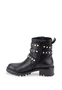 Botas de cuero negro hasta el tobillo con una suela gruesa y tachuelas metálicas en tono dorado a lo largo de las correas. Cuenta con un cierre lateral y una tira para tirar.
