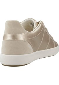 Sneaker beige con una finitura satinata liscia, tallone testurizzato, suola chiara a contrasto e sistema di allacciatura con dettagli metallici.