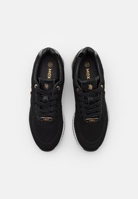 Chaussures de sport noires avec empeigne en mesh texturé, accents dorés et semelles en caoutchouc blanches. Design à lacets et col rembourré pour plus de confort. Taille 37.