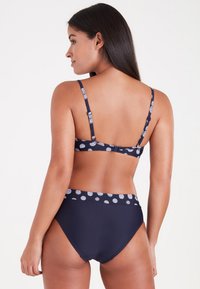 Navy-Bikini-Set mit einem gepunkteten Muster auf dem Oberteil und am Bund. Das Oberteil hat verstellbare Träger und einen klassischen Schnitt für die Unterteile.