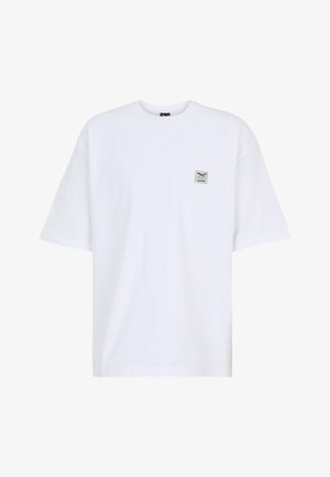 T-shirt bianca oversize a maniche corte con un piccolo logo quadrato con forbici incrociate e testo sul petto sinistro.