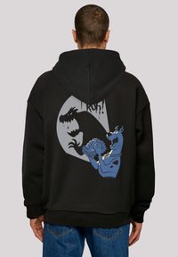 Felpa nera con cappuccio caratterizzata da una grande grafica sul retro con Scooby-Doo e una silhouette di dinosauro, evidenziando colori a contrasto e design da cartone animato.