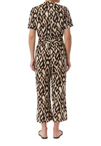 Kombinezon wzorzysty z lekkiego materiału, z abstrakcyjnym wzorem w kolorach czarnym, kremowym i brązowym, krótkimi rękawami i zebranym w talii.