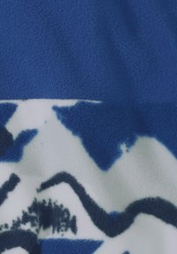 Ύφασμα από φλις σε μπλε και λευκό με αφηρημένα σχέδια βουνών και δέντρων σε σκούρους μπλε και μαύρους τόνους.