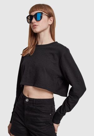 Black cropped sweatshirt with long sleeves, crew neck, and a smooth texture, paired with oversized black sunglasses featuring blue lenses.