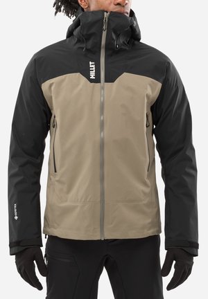 Veste en Gore-Tex avec un devant beige et des épaules noires, fermeture éclair à l'avant, col haut et poignets ajustables. Comprend des poches de chaque côté.