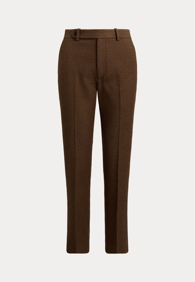Pantalon marron à carreaux, coupé sur mesure, avec passants pour ceinture et fermeture par bouton sur le devant, présenté sur un fond clair uni.