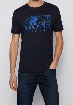 Sort bomuld T-shirt med grafisk tryk foran med blå tekst "BOSS" og "HUGO BOSS," afslappet pasform, rund halsudskæring, korte ærmer.