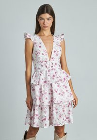 Blumenkleid in Weiß mit rosa Blumen, tiefem V-Ausschnitt, Rüschensäumen, Peplum-Taille, geschichteter Rock und dekorativer Gürtelring-Detail.