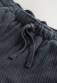 Jogging en gris foncé en tissu texturé et côtelé avec une taille élastique et un cordon de serrage pour l'ajustement.