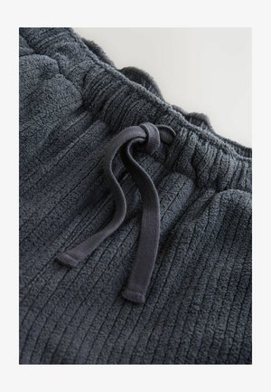 Dark grey joggers made of textured, ribbed fabric with an elastic waistband and a drawstring for adjustment.