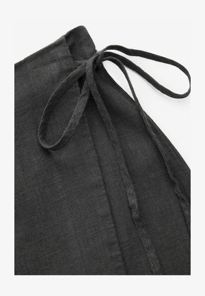 Sort linned apron med båndlukning. Har en tekstureret overflade og et enkelt, funktionelt design. Flad læg visning, der fremhæver detaljerne.