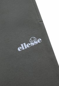 Tejido de sudadera gris con una textura suave, con un logo blanco de "ellesse" impreso de manera prominente. Diseño simple y moderno sin patrones.