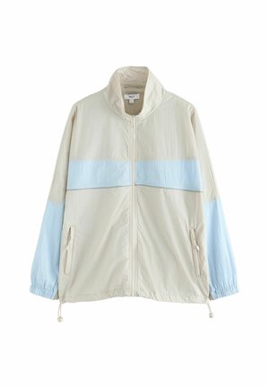 Veste beige clair à fermeture éclair avec une bande horizontale bleu clair traversant la poitrine et les manches, poignets élastiques et ourlet à cordon de serrage.