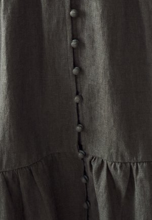 Vestido de lino gris oscuro con un frente abotonado, botones redondos y texturizados, y un dobladillo fruncido. La tela tiene un aspecto suave y ligeramente arrugado.