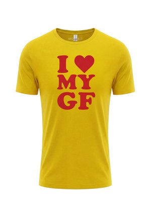 Żółta koszulka z okrągłym dekoltem z wyraźnym czerwonym napisem "I [serce] MOJĄ DZIEWCZYNĘ" na środku przodu.